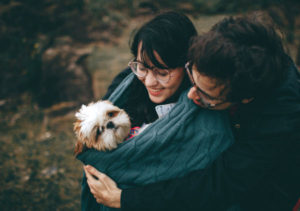 Couple cuddling a small dog and possibly rewarding fear